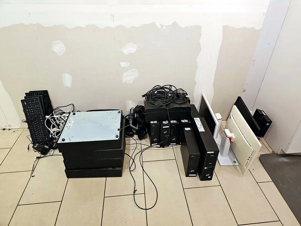 Gestapelte Rechner, Monitore und Tastaturen auf dem Boden eines leeren Büros